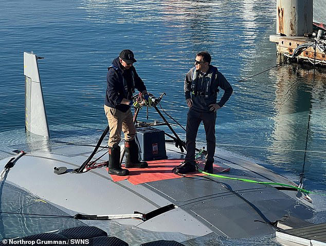 DARPA program manager Dr. Kyle Woerner (right) talks with a member of the Northrop Grumman team while standing atop the Manta Ray vehicle. The Manta Ray prototype completed full-scale testing off the coast of Southern California