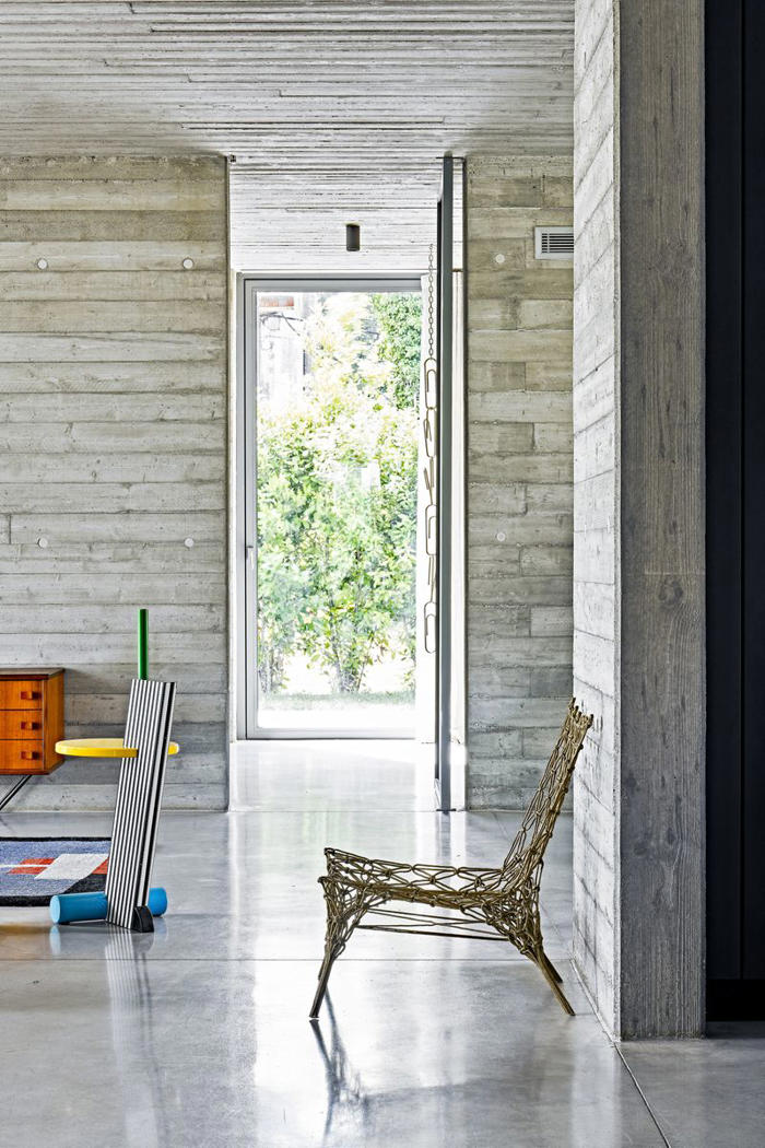 una casa moderna de estilo brutalista con unos interiores que revitalizan el hormigón con muebles de diseño a todo color de inspiración ochentera