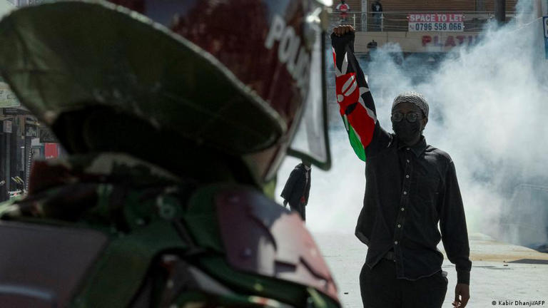 Manifestante segura uma bandeira queniana em frente a um membro das forças de segurança