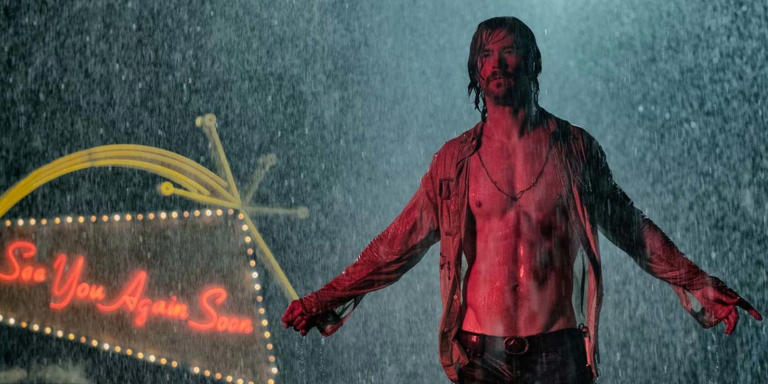Billy Lee stands in the rain with the hotel sign behind him