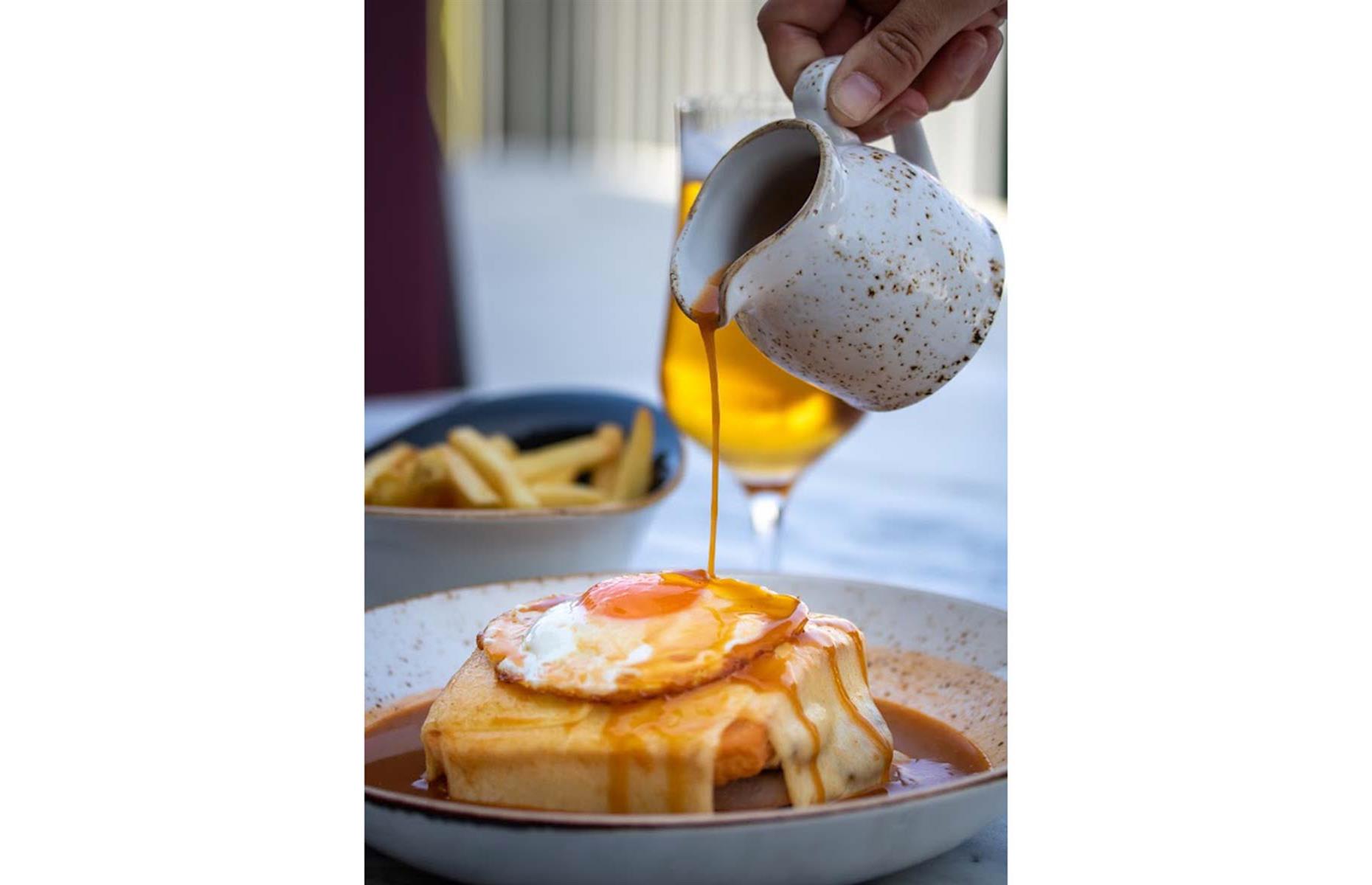 <p>At its core, the francesinha is a sandwich filled with layers of cured meats, such as linguiça, fresh sausage, steak, and ham, topped with a gooey layer of melted cheese and then all smothered in a rich tomato and beer sauce. Locals will say it must be crowned with a perfectly fried egg and served with the crunchiest matchstick fries imaginable. This carb-heavy comfort food is both savory and spicy, and perfect for the day after some heavy wine sampling.</p>