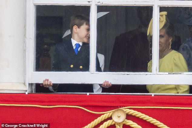 Prince Louis is pictured trying to open a window on a balcony on Horse Guards Parade next to the Duchess of Edinburgh