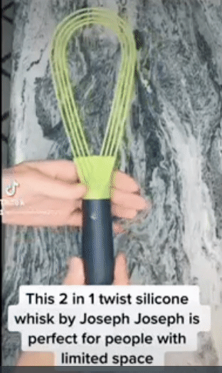 A person twisting a green flat whisk to turn into a balloon whisk
