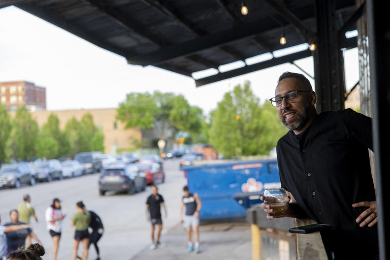 Monochrome Brewing co-owner Enrique Rivera looks out over the patio at guests who came to the soft opening of the brewery on May 1, 2024, in the Pilsen neighborhood.