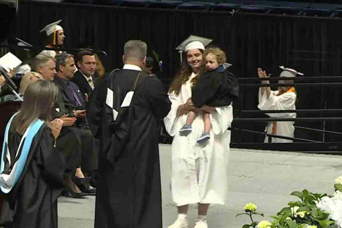 etter mange kamper, mottar en studentinnen sin videregående skole diplom med sønnen i armene