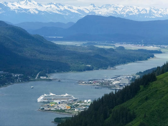 A cruise ship dwarfed by nature as it rests beside the Juneau docks in June 2017 (AP Photo/Becky Bohrer)