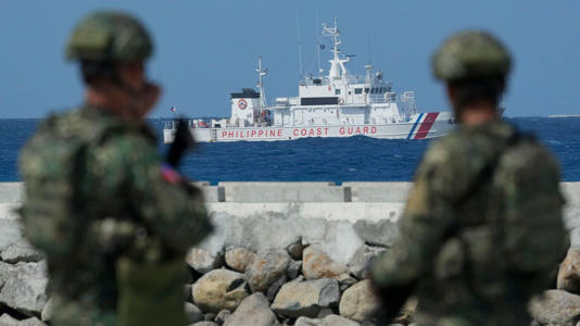 Philippine troops watch a Philippine Coast Guard ship as they secure an area at the Philippine-occupied Thitu island, locally called Pag-asa island, on Dec. 1, 2023, in the disputed South China Sea. AP Images