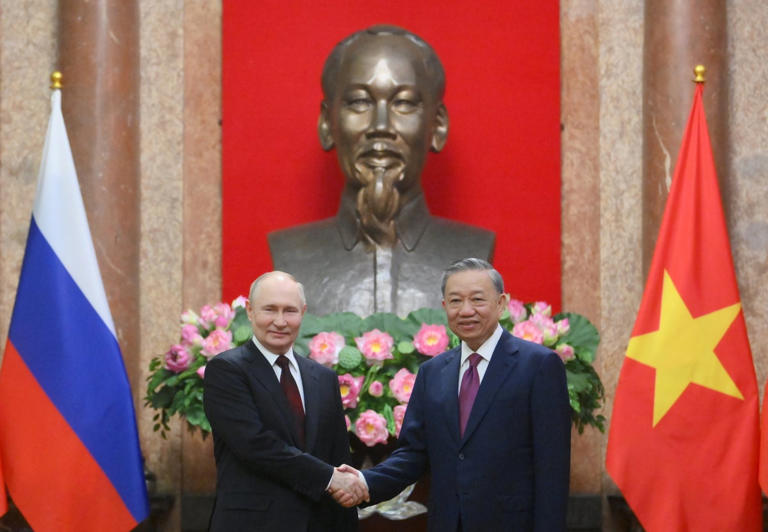 Vietnamese President To Lam (R) and his Russian counterpart Vladimir Putin (L) pose for photos at the Presidential Palace in Hanoi