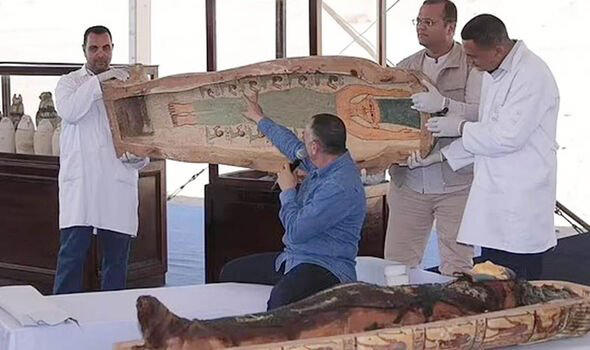 Archaeologists lifting the lid of a sarcophagus