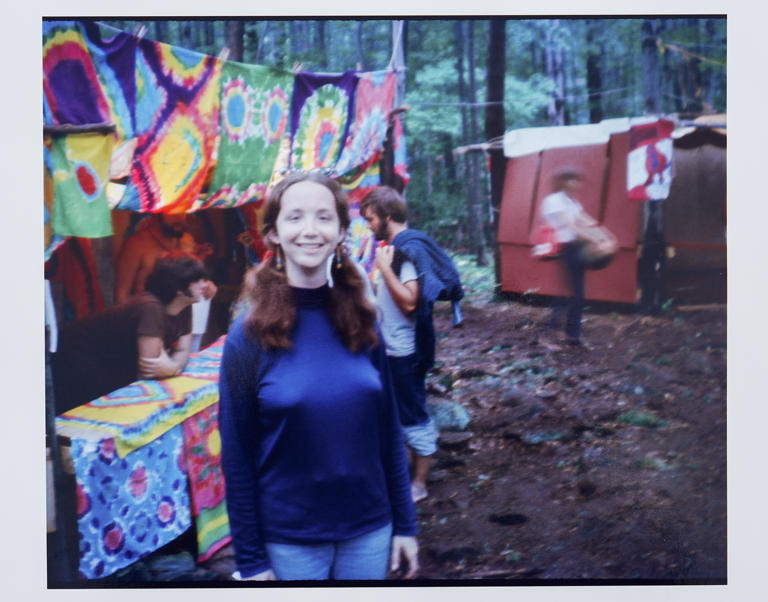 Esta fotografía de agosto de 1969 muestra a Ellen Shelburne, caminando por los terrenos de la Feria de Arte y Música de Woodstock en Bethel, Nueva York. El Centro para las Artes Bethel Woods, la organización sin fines de lucro que administra el sitio, desplegó la alfombra teñida de colores para Shelburne y su amiga, Beverly Grant (que no aparece en la foto) para promocionar sus nuevas instalaciones de campamento de lujo y revisar el tesoro de fotografías de Shelburne del festival que definió a una generación, celebrado del 15 al 18 de agosto de 1969. (David Shelburne via AP)
