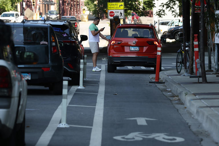 A motorist enters his vehicle parked in a bicycle lane in the 500 block of West Kinzie Street, June 29, 2022, in Chicago.