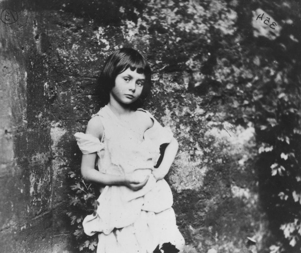 <p>Alice Liddell was one of ten children born to the Dean of Christ Church in Oxford. The family met Lewis Carroll, whose actual name is Charles Lutwidge Dodgson, while he was photographing the cathedral. He went on to be a close friend of the family.</p> <p>Six years after meeting, Alice asked Charles to write a story to entertain her and her sisters while they sailed the Thames. Alice loved the story about the girl who falls into the rabbit hole so much, that she asked him to write it down for her. The original manuscript was published as <i>Alice's Adventures Under Ground</i>.</p>