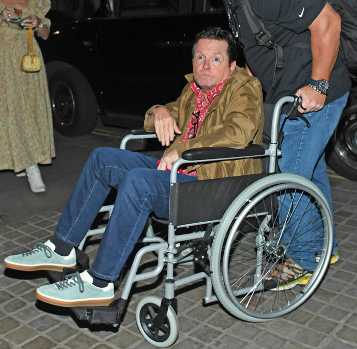 michael j fox flashes peace sign from wheelchair amid devastating parkinson's battle