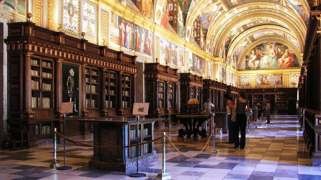 <p>The Library at El Escorial dates back to the 1580s. It is part of a complex that also includes a church, a palace, a college, and a monastery. Probably one of the most striking features of the library is its unified artistic theme. The paintings on the walls and ceilings embody 17th-century art and architecture.</p><p>This idea of maintaining coherence in the overall design helps preserve and showcase the building’s history and significance while also adding to its classic appeal. Notably, El Escorial is recognized as a UNESCO World Heritage Site.</p>