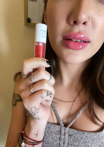 Reviewer holding the appleberry lip oil with it applied on lips