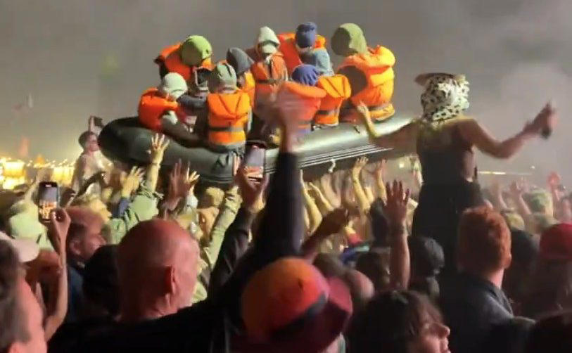 watch: banksy’s migrant boat sails across glastonbury crowd