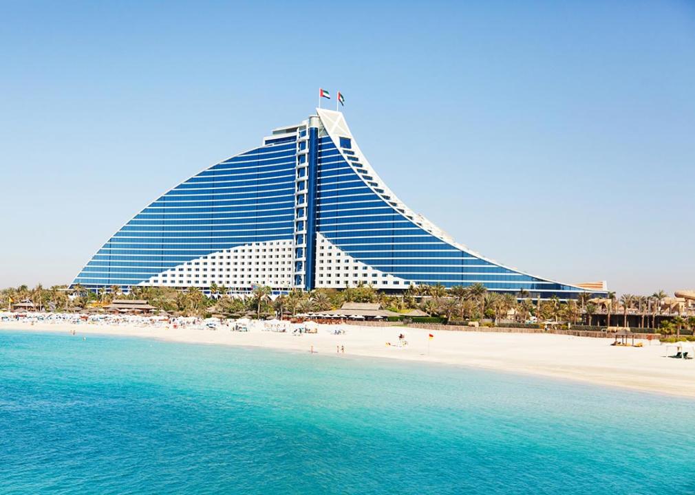 <p>Situated on Jumeirah Beach Road, the Jumeirah Beach Hotel is conveniently located near the iconic Burj Al Arab and Madinat Jumeirah, and is a mere 30-minute drive from Dubai International Airport. Designed with families in mind, this hotel offers a wide array of activities and amenities tailored to all ages.</p>  <p>The hotel's architecture is a visual marvel, resembling a stunning breaking wave with a curved design in both its plan and elevation. Inside, the decor theme is inspired by the four elements of nature—Earth, Air, Fire, and Water—each represented through distinctive color schemes across four levels of the hotel. These range from calming blues and greens for water, earthy browns and reds for earth, airy blues and whites for air, to vibrant reds and yellows for fire.</p>  <p>This award-winning resort features 26 floors with 617 sea-facing rooms, suites, and villas, each offering about 50 square meters of space. Additionally, there are 19 Arabian-themed Beit Al Bahar villas, providing exclusive amenities like private check-in, <a href="https://honeymoons.com/sandals-butler-service/">butler service</a>, individual plunge pools, private terraces, and access to a secluded pool area.</p>  <p>For younger guests, the hotel hosts Sinbad's Kids Club, a ship-shaped clubhouse near the family pool. It offers a variety of activities for children aged 2-12, supervised by highly trained staff. Babysitting services are also available.</p>  <p>Guests can access the adjacent Wild Wadi Water Park, a unique attraction in the Middle East. The Pavilion sports club, located on the Marina breakwater, offers a range of activities including diving (PADI 5 star), squash, tennis, a gymnasium, and various water sports, all with qualified instruction available.</p>  <p>For relaxation, the health club features saunas, hot tubs, steam rooms, Jacuzzis, plunge pools, massage rooms, and a range of treatments. There are five external swimming pools, including the main leisure pool with features like a walk-in Jacuzzi, chilled plunge pool, submerged airbeds, and a swim-up bar. The family pool has a 'beach' entrance and a water slide, while the other three pools include a shaded children's pool with water play equipment, a 25m lap pool, and the exclusive Executive Pool with underwater sound system and bubble coves.</p>  <p>Additional outdoor facilities include a mini putting green, golf driving nets, a children's adventure park, and complimentary access to Wild Wadi Water Park.</p>