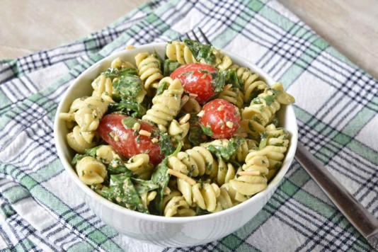 Pasta con espinacas y queso dentro de plato blanco 