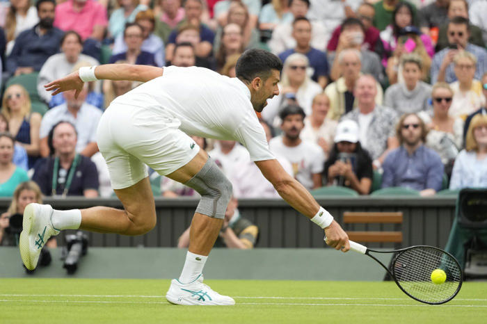 novak djokovic wins his first match at wimbledon with a sleeve on his surgically repaired knee