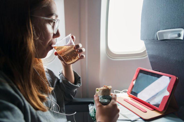 A woman eating a sandwich on a plane (Stock)