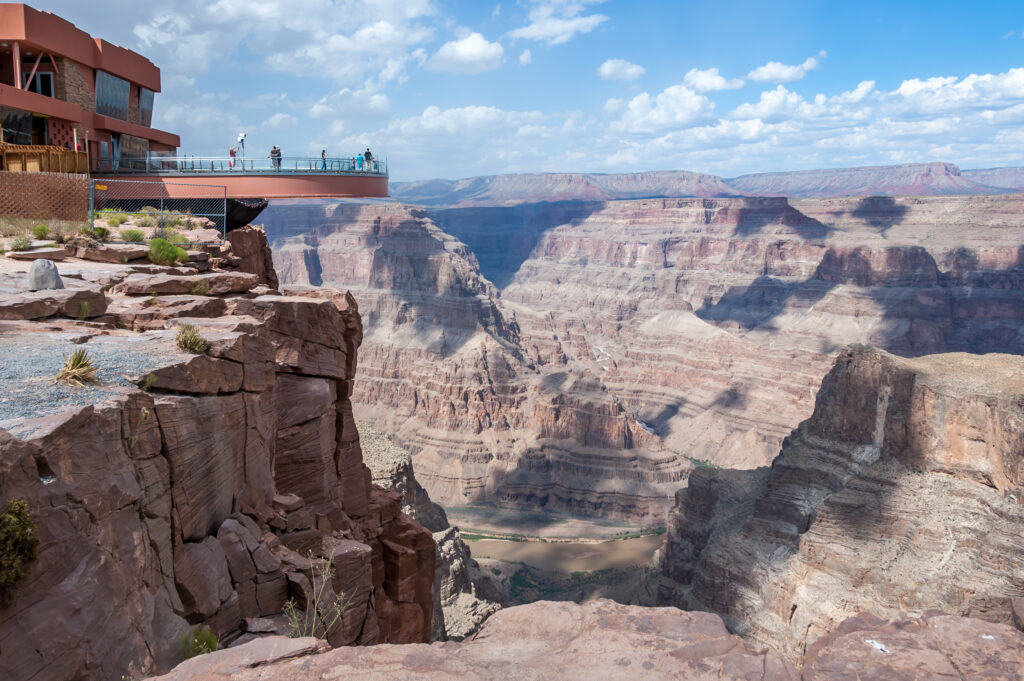 <p>The Western Rim is the closest part of the Grand Canyon to Las Vegas. Here, you’ll find Grand Canyon West which is home to the famous <strong>Skywalk</strong>. Unlike the sections controlled by the National Park Service, Grand Canyon West is located on sovereign lands of the <strong>Hualapai Tribe</strong>. Visitors to Grand Canyon West help support the Hualapai people as funds help to protect their natural resources and heritage.</p> <p>The Hualapai Tribe lives on over one million acres along 108 miles of the Grand Canyon and Colorado River, including a particularly scenic 17.6 mi² they set aside for visitors at Grand Canyon West. The canyon here is almost 4,000′ deep and 3-miles across. The tribe has facilitated multiple ways for you to enjoy the deep gorges and red rock buttes that are quintessentially the Grand Canyon.</p>