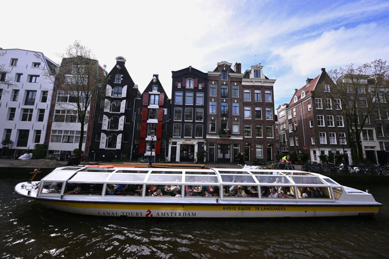 A tourist boat cruises along a canal in Amsterdam.