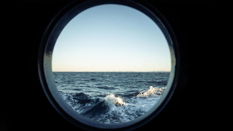 Water is seen through a porthole on a cruise ship. -lead