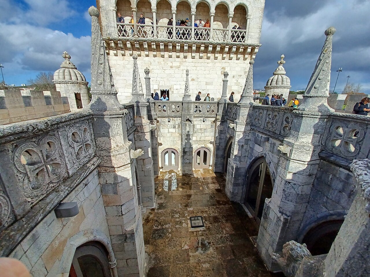 The tower, situated on the northern bank of the Tagus River, is an architectural masterpiece known for its exquisitely rich exterior, featuring sculpted balconies and limestone ornaments. The influence of Moorish architecture is evident in the delicate decorations, arched windows, and ribbed cupolas of the watchtowers.