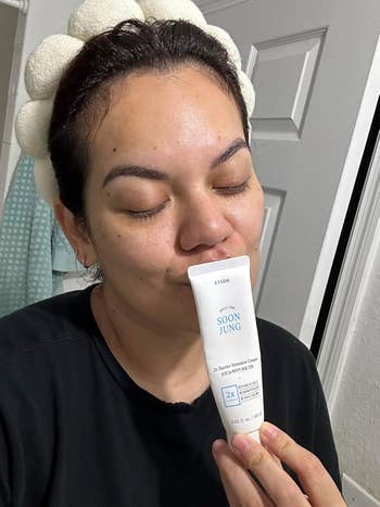 a reviewer kissing the bottle of moisturizer