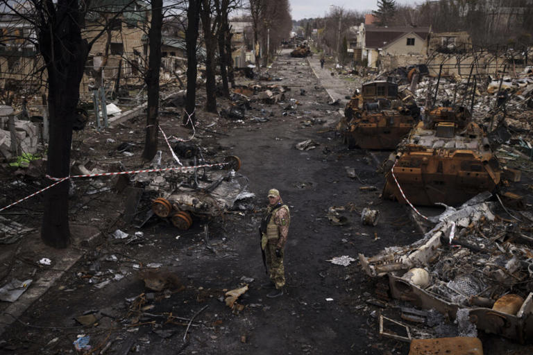 A Ukrainian serviceman stands amid destroyed Russian tanks in Bucha, on the outskirts of Kyiv, Ukraine, April 6, 2022. Felipe Dana/AP/File