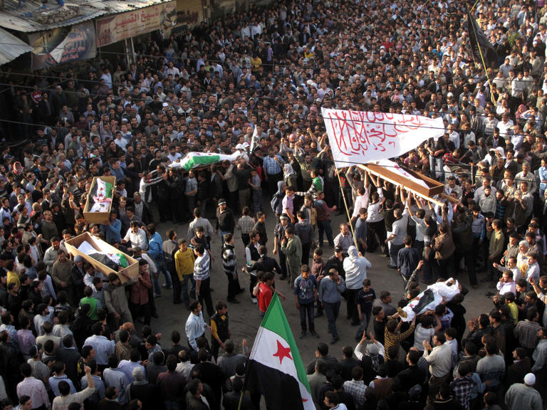 Mourners carry bodies draped in the Syrian revolutionary flag during the funeral for four people killed in a raid by government forces in Damascus in 2012.