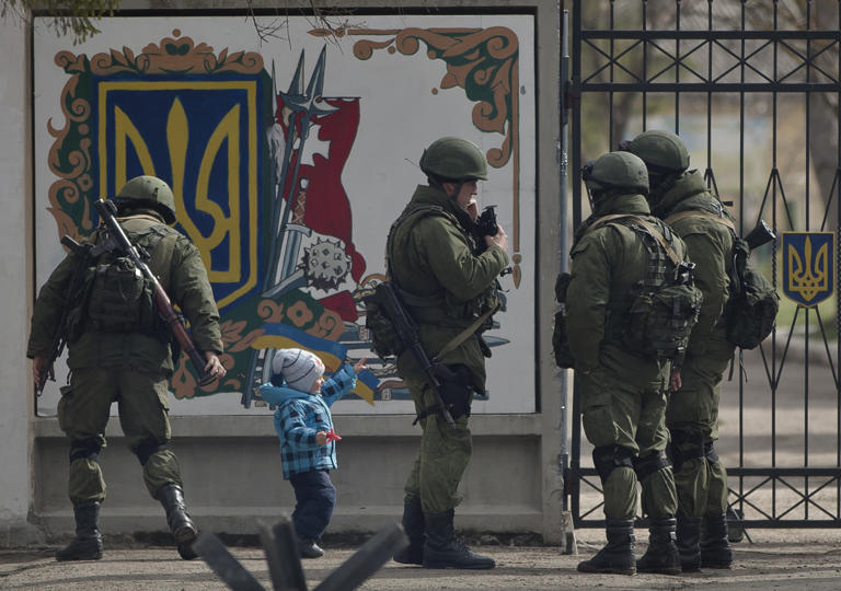 A child walks among pro-Russian soldiers near a Ukrainian military base that they surrounded in Crimea in March 2014.