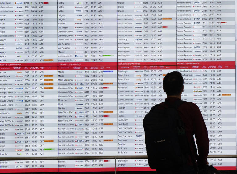 A passenger checks departure times at Trudeau International Airport Friday, July 19, 2024 in Montreal. Environmental activists have disrupted operations at Montreal's Trudeau airport for a third consecutive day in protest of Canadian fossil fuel policy. THE CANADIAN PRESS/Ryan Remiorz