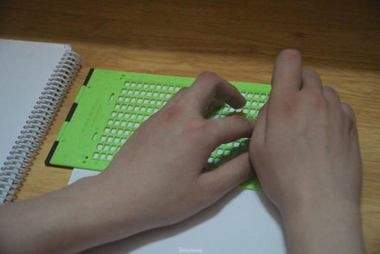 Khánh viết chữ Braille (chữ nổi) trên giấy mỗi khi học bài.