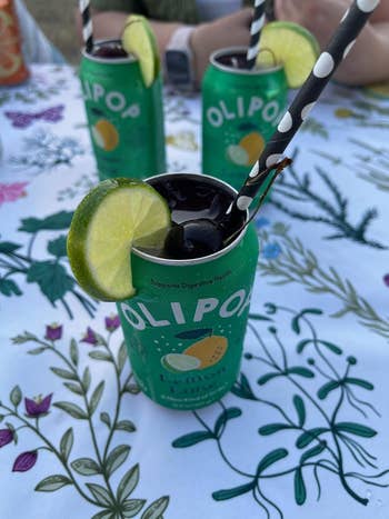 Topless Olipop lemon-lime soda cans with straws and lime slices
