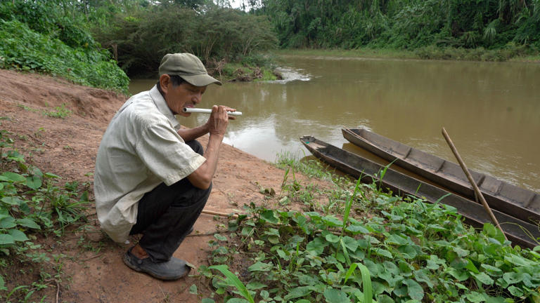 Fermin toca la flauta frente al rio Maniqui, su principal fuente de alimentos.