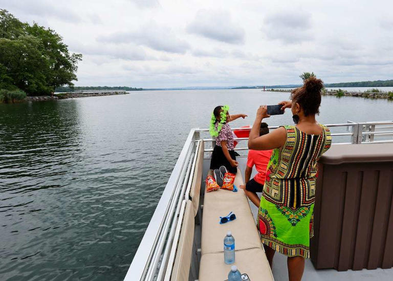 Nikita Jankowski takes a snapshot of her children, Noble and Xochi, aboard Syracuse Boat Tours' 30-ft pontoon boat as it cruises down the Onondaga Lake outlet.
