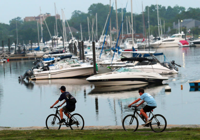 Kids ride their bikes along the water in Harbor Island Park in Mamaroneck June 30, 2023. The 44-acre tract next to Mamaroneck Harbor offers a playground, beach, boat launch and sports fields. Most of the park sits atop soil, rock and other materials used to fill in environmentally valuable tidal wetlands in the early 20th Century.