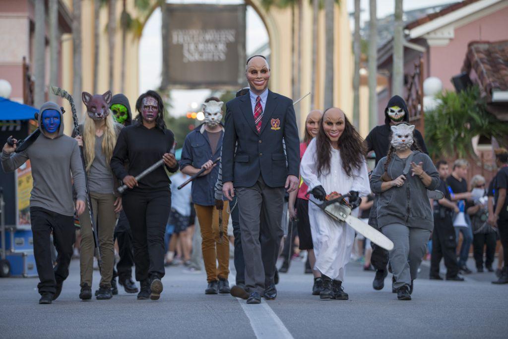 Purge characters with masks and props for Purge Anarchy Scare Zone at Halloween Horror Nights 2014. Keep reading to find out more about Halloween Horror Nights scare zones.