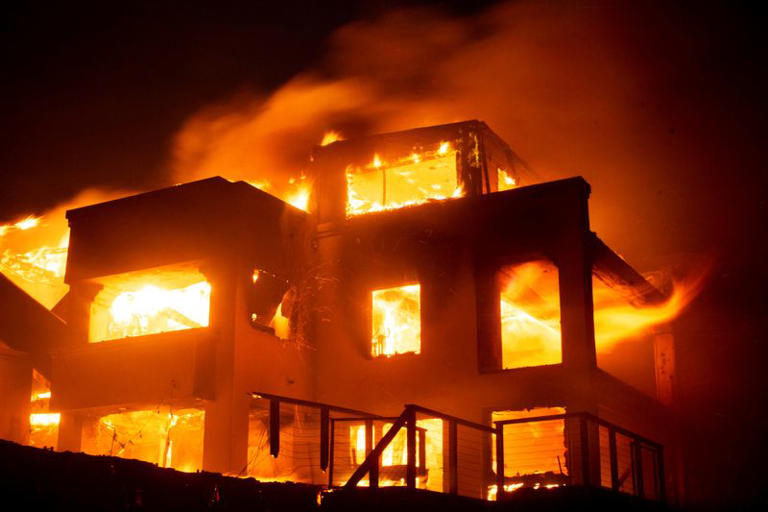 Flames rise from a structure as the Palisades fire burns during a windstorm on the west side of Los Angeles, California, U.S. January 8, 2025. REUTERS/Ringo Chiu