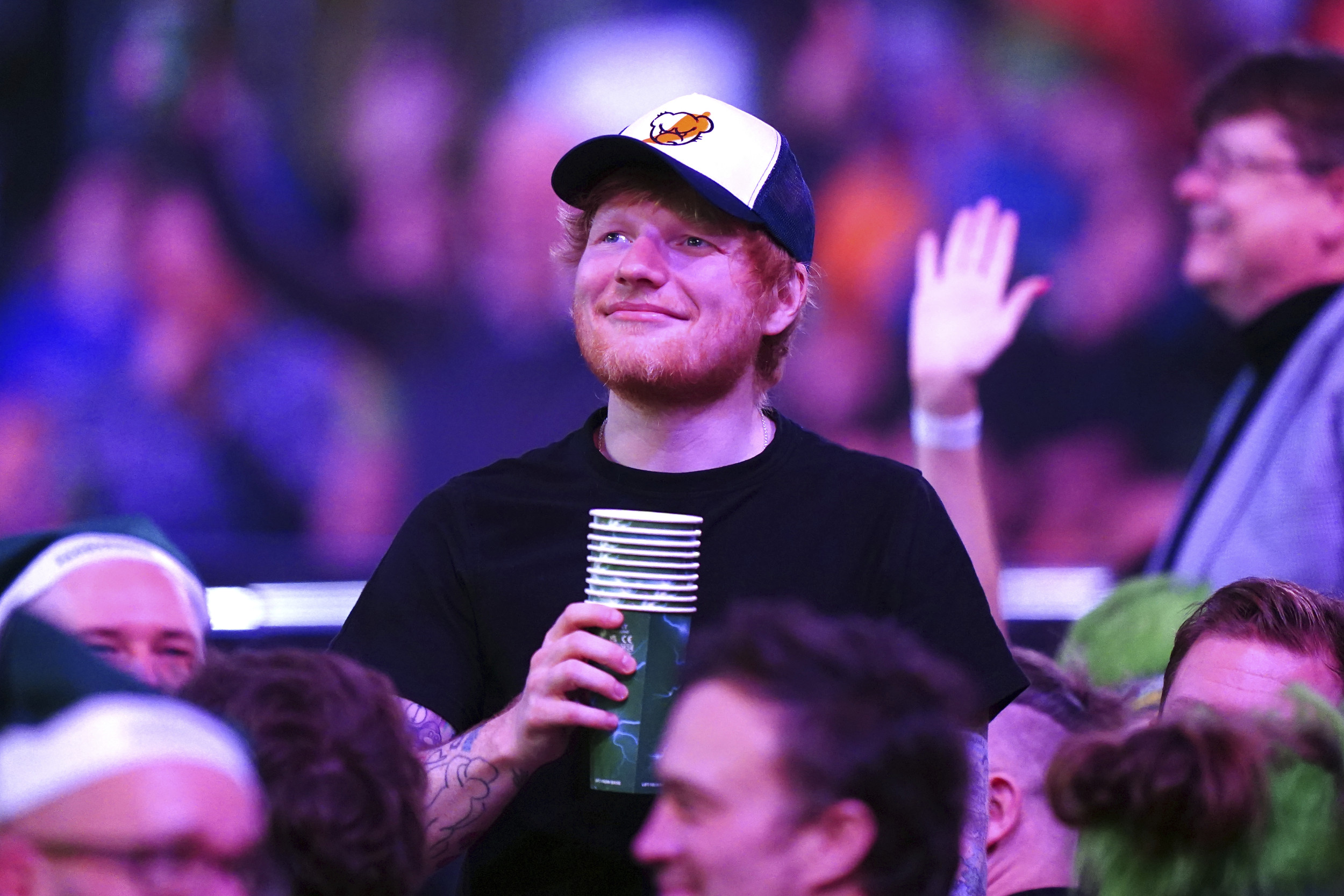 Singer songwriter Ed Sheeran drinks from a cup while being encouraged by the fans during day six of the Paddy Power World Darts Championship at Alexandra Palace, London, Dec. 20, 2024. So far the Ed Sheeran Foundation says it has supported 18 grassroots music education organizations or state school music departments, which will improve access to instruments and lessons for 12,000 children. AP Photo