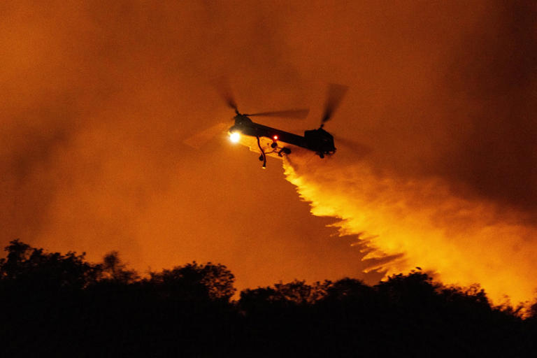 米カリフォルニア州ロサンゼルスの山火事で水を投下するヘリコプター＝11日（AP＝共同）