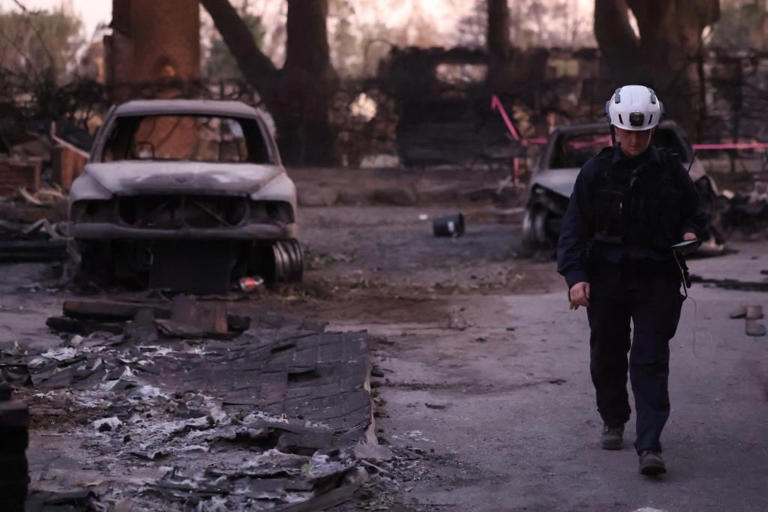 Un miembro de búsqueda y rescate del condado de Marin camina junto a un automóvil quemado por una carretera desierta destruida por el incendio de Eaton en Altadena el 11 de enero de 2025. | Crédito: REUTERS