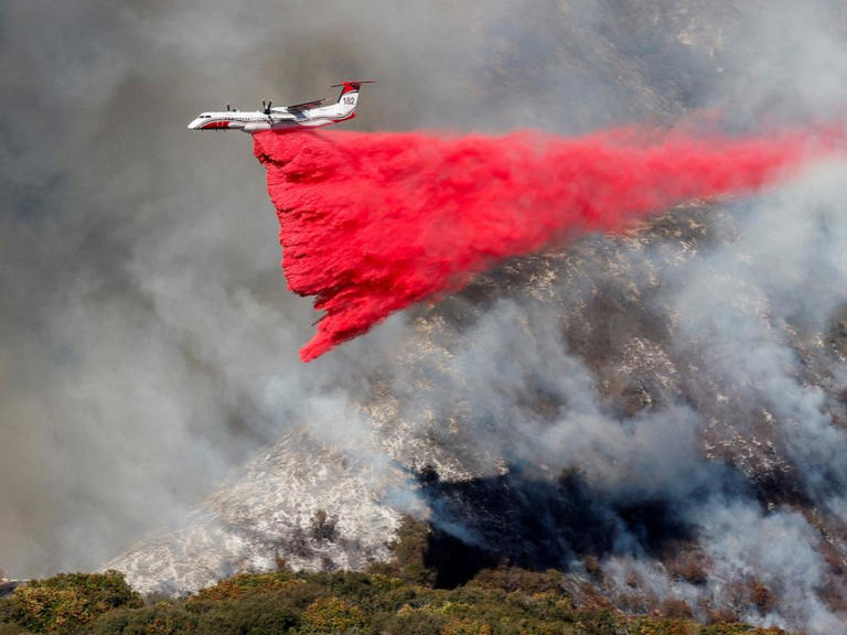 A plane makes a drop as smoke billows from the Palisades Fire at the Mandeville Canyon, in Los Angeles, Calif., Jan. 11, 2025.
