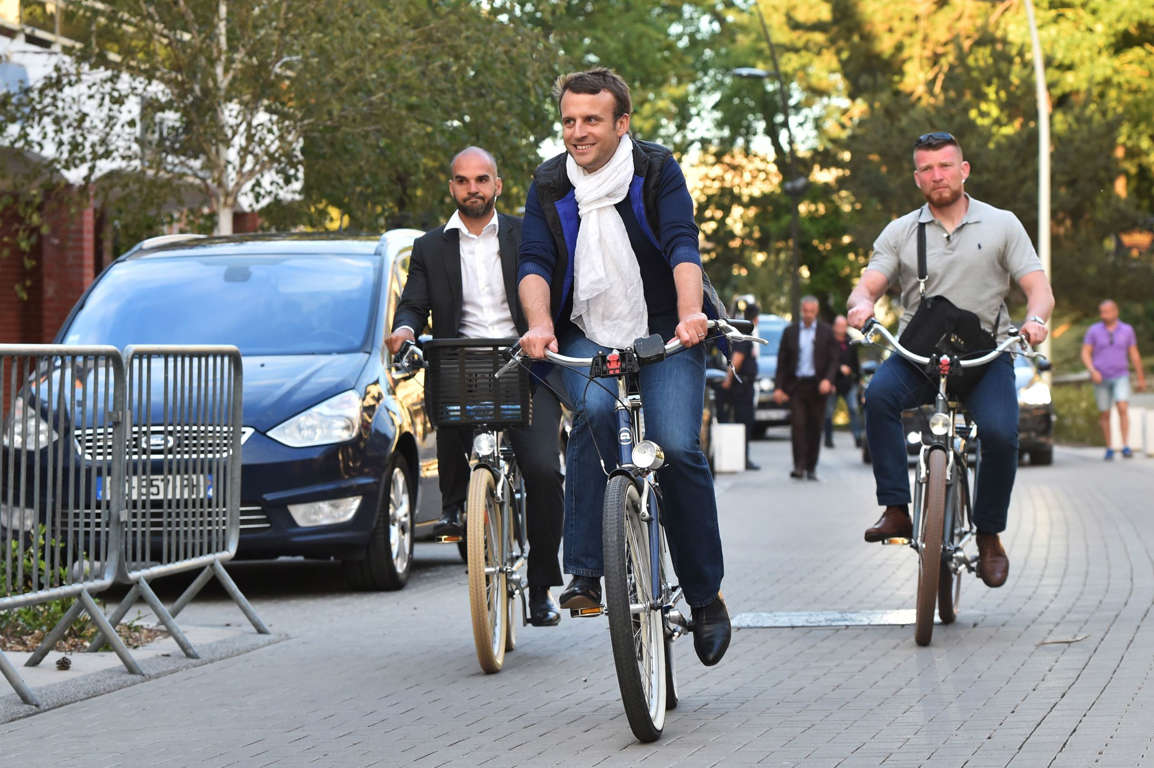Slide 16 of 33: TOPSHOT - French President Emmanuel Macron (C) takes a bicycle ride on June 10, 2017, in Le Touquet, northern France, the city where Macron votes, on the eve of France's legislative elections.
?French voters go to the polls on June 11, 2017, in the first