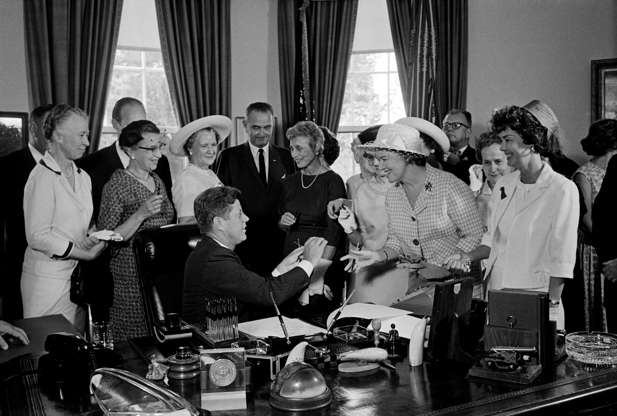 Slide 8 of 13: President Kennedy hands out pens during a ceremony at the White House today in which he signed into law a bill aimed at assuring women of paychecks equal to those of men doing the same work. Left to right: Esther Peterson, Assistant Secretary of Labor; Evelyn Christensen, National Board of YWCA; Rep. Leonor Sullivan (D-Missouri); Vice President Lyndon Johnson; Mrs. Joseph Willen, National Council of Jewish Women; Dr. Minnie Miles, National Federation of Business and Professional Women's Clubs (partially hidden); Miss Margaret Mealey, National Council of Catholic Women; Andrew Biemiller, AFL-CIO Official; Rep. Edith Green (D-Oregon); and Mrs. Garlyn Davis.