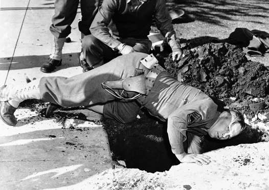 Slide 2 of 13: An army demolition squad moved right in to take things over after an unexploded anti-aircraft shell fell in the yard of George Watson at Santa Monica, Calif., Feb. 26, 1942, when it was thrown up in the great barrage of fire from army guns during an air raid alarm in the Los Angeles area on February 25. Sergeant C.M. Weathers reaches down to remove it. (AP Photo)