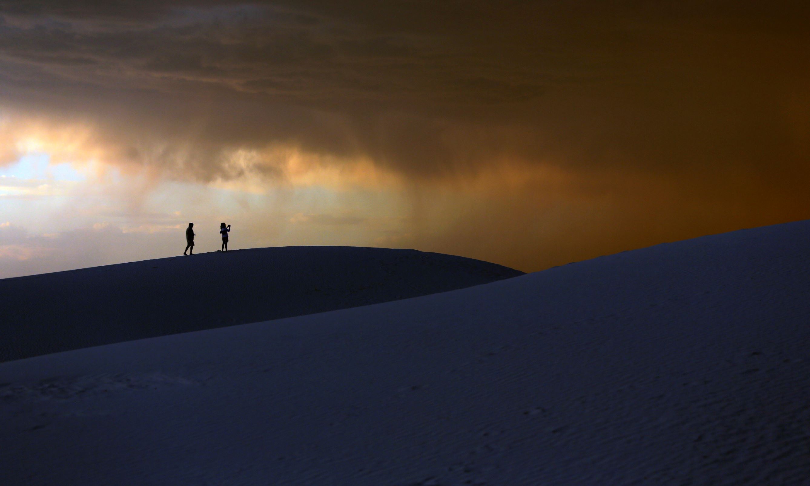 Slide 3 of 40: A storm moves in over a couple visiting White Sands National Monument, Wednesday, June 21, 2017, near Alamogordo, N.M. Temperatures in the area hit 105 degrees Wednesday. (AP Photo/Eric Gay)