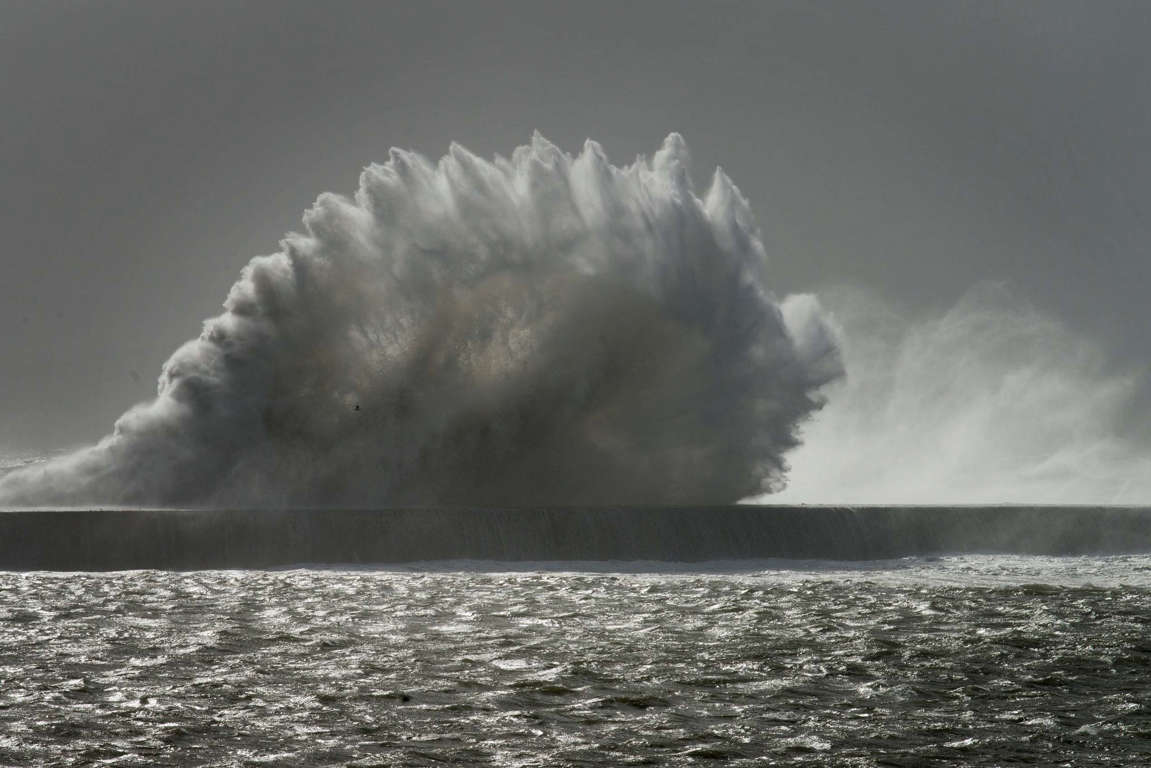 Slide 6 of 40: Waves break over a sea wall at Cape Town harbour on June 7, 2017, as an intense storm hits South Africa's west coast.