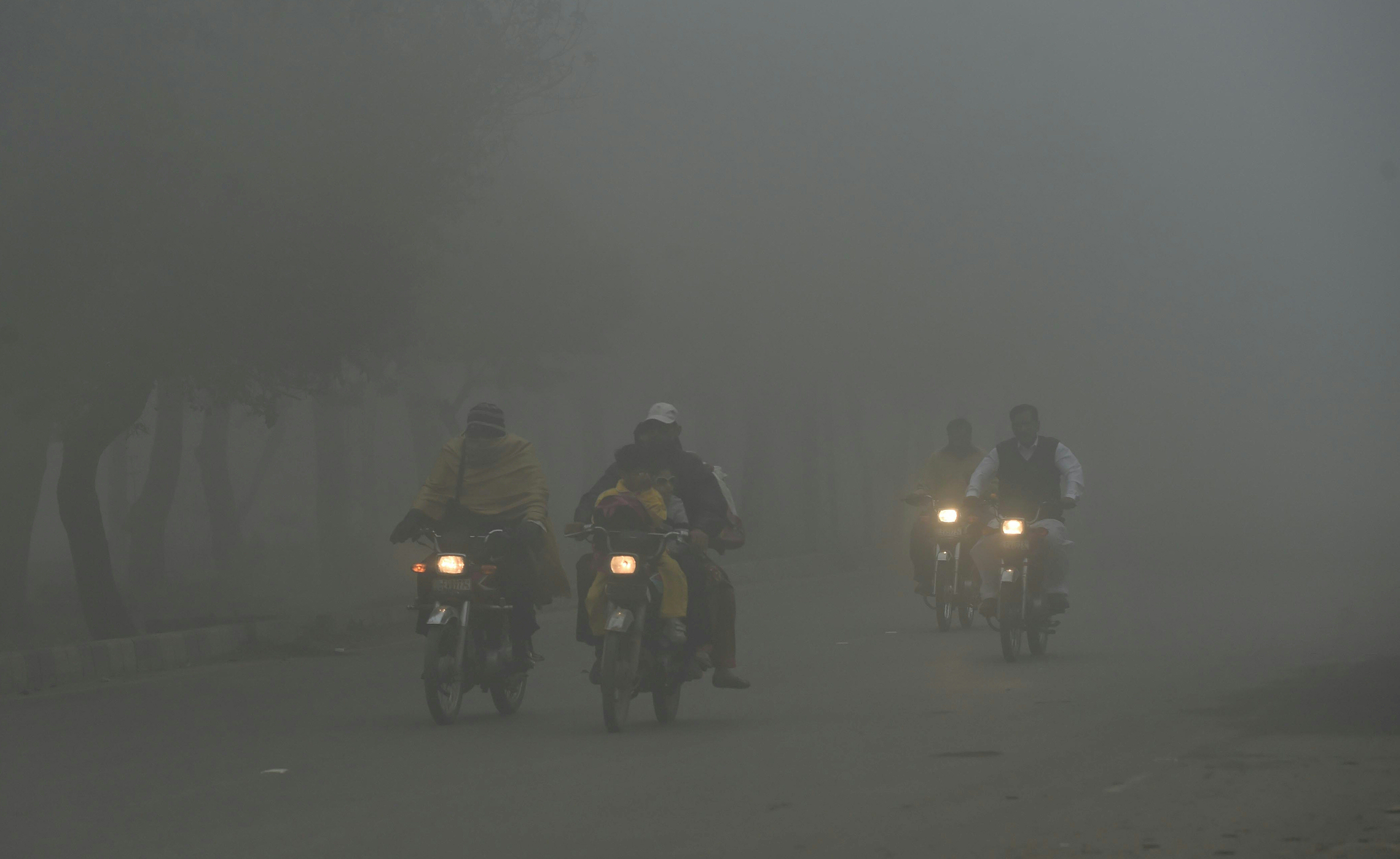 Slide 8 of 26: Pakistani motorcyclists ride along a street amid heavy smog in Lahore on Nov. 9, 2017. Flights were cancelled, school times pushed back and hospitals flooded as air pollution inundated Pakistan's second largest city Lahore. The fast-developing country suffers from some of the worst air pollution in the world, thanks to its giant population navigating poorly maintained vehicles on its roads and unchecked industrial emissions along with seasonal crop burning.